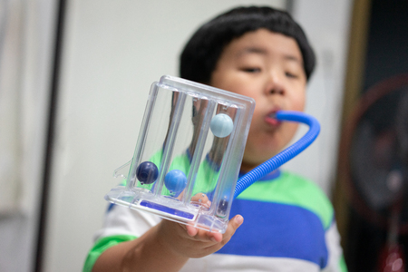 A fat boy is testing and administering lungs with a tri-ball dryer.の写真素材