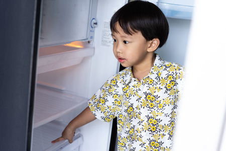 The boy is helping his mother to work at home and picking up water from fridge to his mom.の写真素材