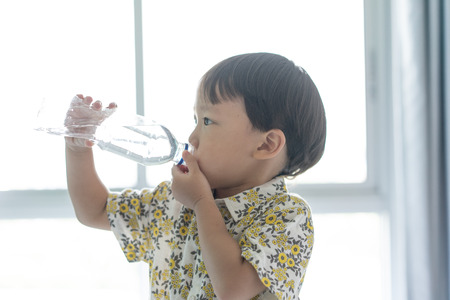 A boy is drinking a bottle of water.
