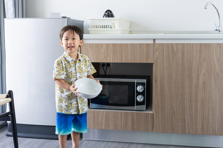 A boy is cooking his breakfast by microwave in kitchen in the morningの写真素材