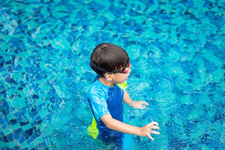A boy is playing and swimming at the swimming pool in the evening.の写真素材
