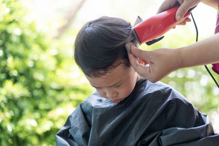 Grandma was cutting hair for her nephew at home in the garden during the day time.