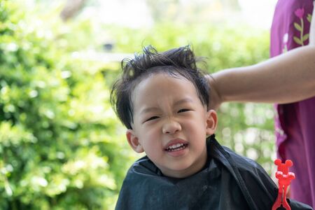 Grandma was cutting hair for her nephew at home in the garden during the day time.の写真素材