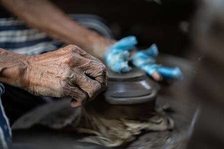 Close-up hands of a male potter. Artist is making a vase from clay, selective focus.の写真素材