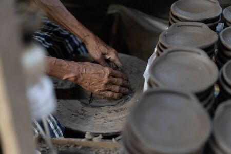 Close-up hands of a male potter. Artist is making a vase from clay, selective focus.の写真素材