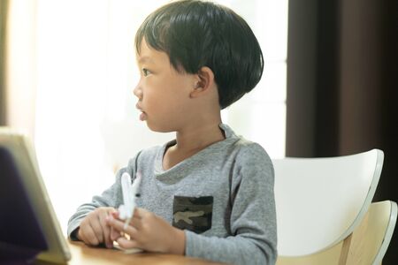 A boy is bored with study online, he wants to play an airplane toy.