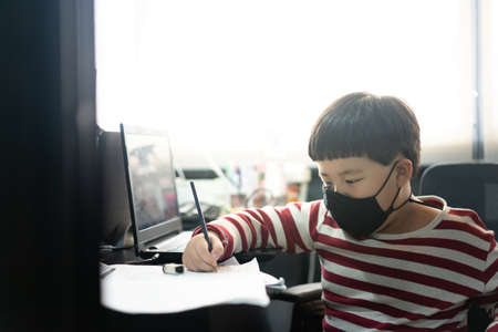 A fat boy is studying online with a tablet and a book at his father's office.の写真素材