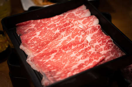 Raw sliced Wagyu beef for shabu shabu on black tray in the japanese restaurant.の写真素材