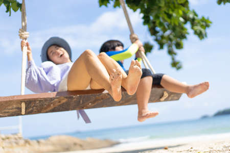 Mother playing on the swing with her children at the beach on holiday.の写真素材