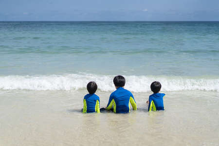 brothers are playing in the sand and swimming at the beach at an island in Thailandの写真素材