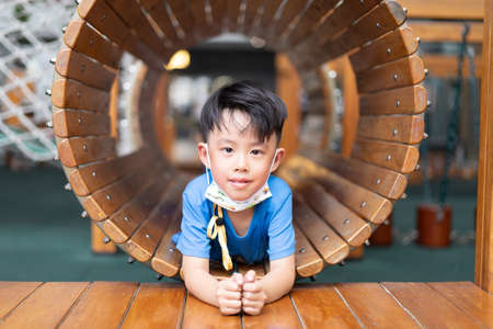 A boy is in a wooden tunnel at a playground.の写真素材