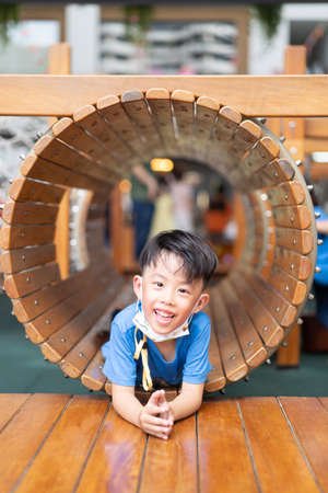 A boy is in a wooden tunnel at a playground.の写真素材