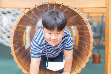 A boy is in a wooden tunnel at a playground.の写真素材