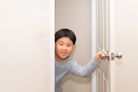 A playful boy peeking from behind the door of the house.の写真素材