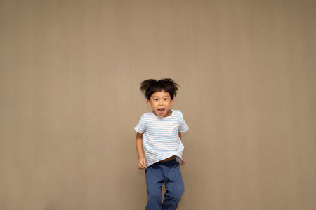 The boy is jumping on the bed at night.