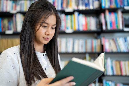 Asian woman is reading a book in the university library.