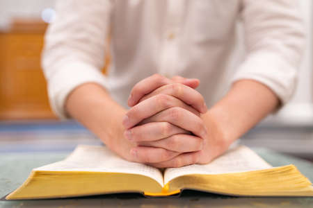 Asian man is reading the Holy Bible and praying in a worship room in a Christian church.の写真素材