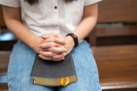 Asian woman is reading the Holy Bible and praying in a worship room in a Christian church.の写真素材