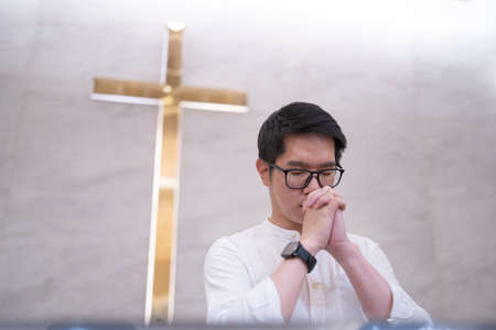 Asian man praying in a worship room in a Christian church.の写真素材