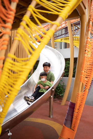 brothers are playing with face masks on playground during quarantineの写真素材