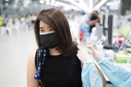 Woman in medical face mask getting   or flu vaccine at the vaccination zone outside the hospital.の写真素材