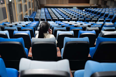 a girl in the empty theatre, conference room with many blue and gray seats.