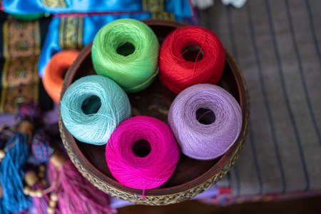 Knitting yarn in balls. In a wicker basket, balls of yarn for knitting. Coziness is created by a cup of tea, a knitting yarn, and knitted clothing. Knitting yarn with a rainbow of colors.の写真素材