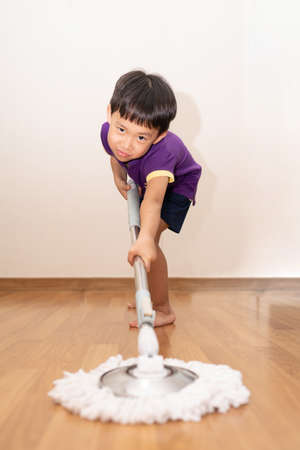 A shot of an adorable little child sweeping and scrubbing the floor at home.の写真素材