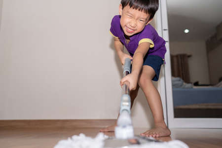 A shot of an adorable little child sweeping and scrubbing the floor at home.