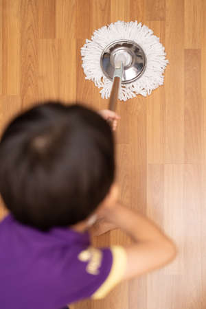 A shot of an adorable little child sweeping and scrubbing the floor at home. Space for text.の写真素材
