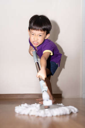 A shot of an adorable little child sweeping and scrubbing the floor at home.の写真素材