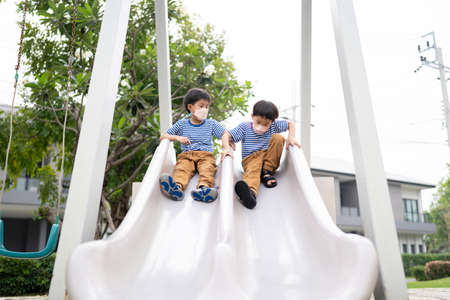 On the playground, two brothers are enjoying each other's company.の写真素材