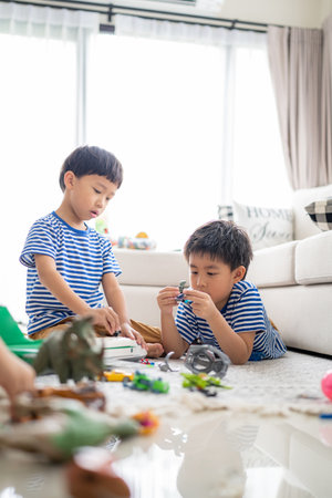 In the living area, brothers are playing with a variety of toys.の写真素材