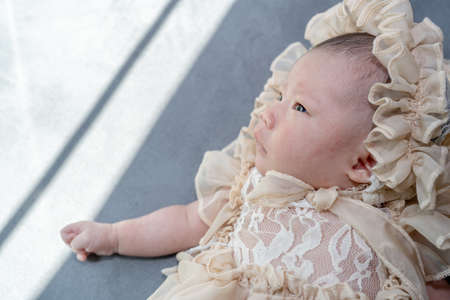 baby girl wearing evening gown dress, She lie comfortably on the bedの写真素材