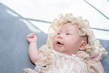 baby girl wearing evening gown dress, She lie comfortably on the bedの写真素材