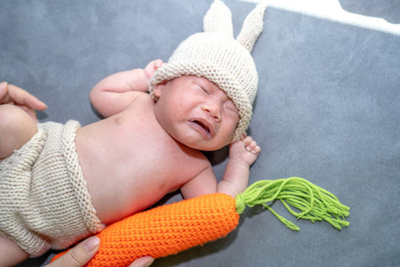 A baby girl dresses up a bunny, playing her carrot pillow.の写真素材