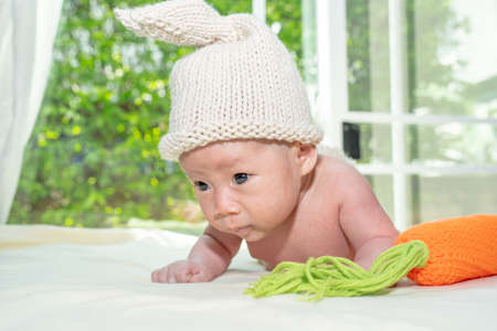 A baby girl dresses up a bunny, playing her carrot pillow.の写真素材