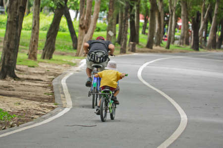 father and son riding bikes in park の写真素材