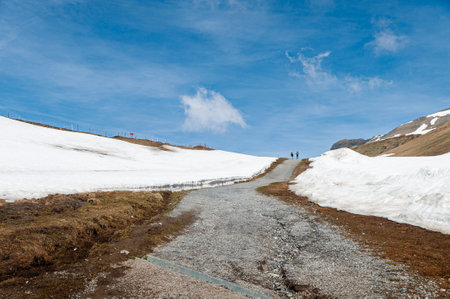 Mountain road in the Swiss Alps with snow and clear blue skyの写真素材