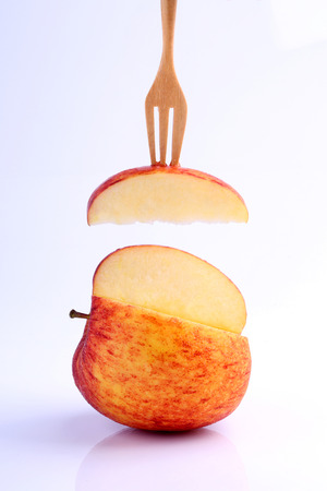 Cool red apple on fork isolated on white background.の写真素材