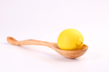 Cool organic fresh ripe lemon on wooden spoon isolated on white background.の写真素材