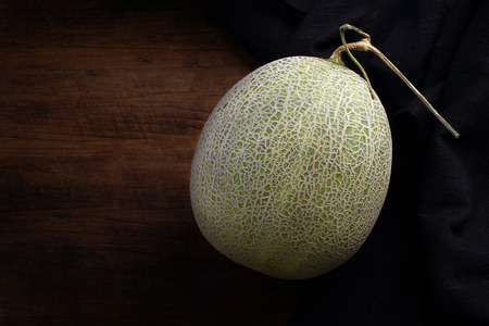 Fresh organic Japanese melon and black fabric on wooden table.の写真素材