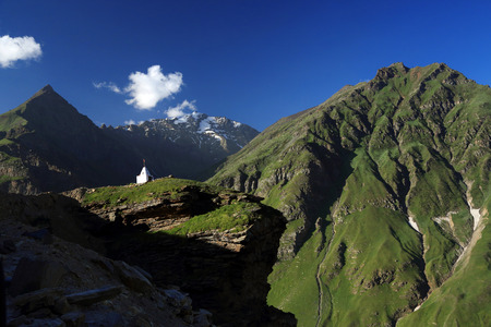 White Tibetan stupa on top of mountain with high mountain background, Northern India.