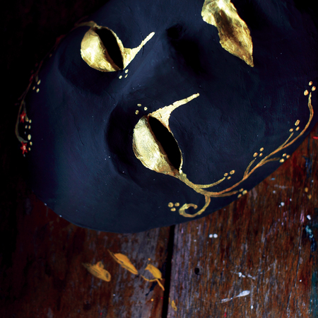 Dark full mask with golden pattern on wooden table.の写真素材