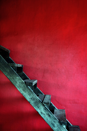 Vintage rusty wooden stair with red cement wall.の写真素材