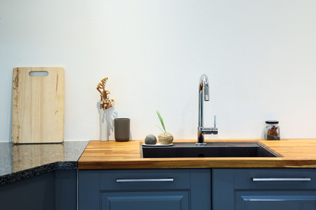 Modern sink with wooden cutting board in kitchen room.の写真素材