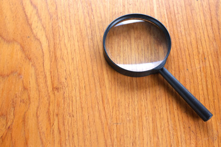 copy space black a magnifying glass on the brown wooden office desk backgroundの写真素材