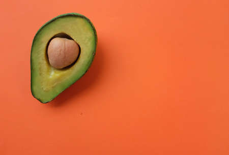 copy space fruit Organic avocado with seed, avocado halves  on bright orange background. creative summer food concept. minimal flat lay styleの写真素材