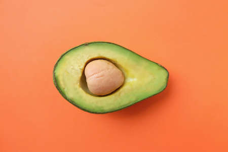 top view and flat lay.fruit Organic avocado with seed, avocado halves  on bright orange background. creative summer food concept. minimal flat lay styleの写真素材