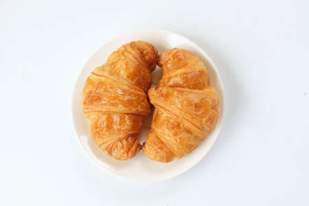 freshly baked croissants on a white circle ceramic plate. breakfast concept